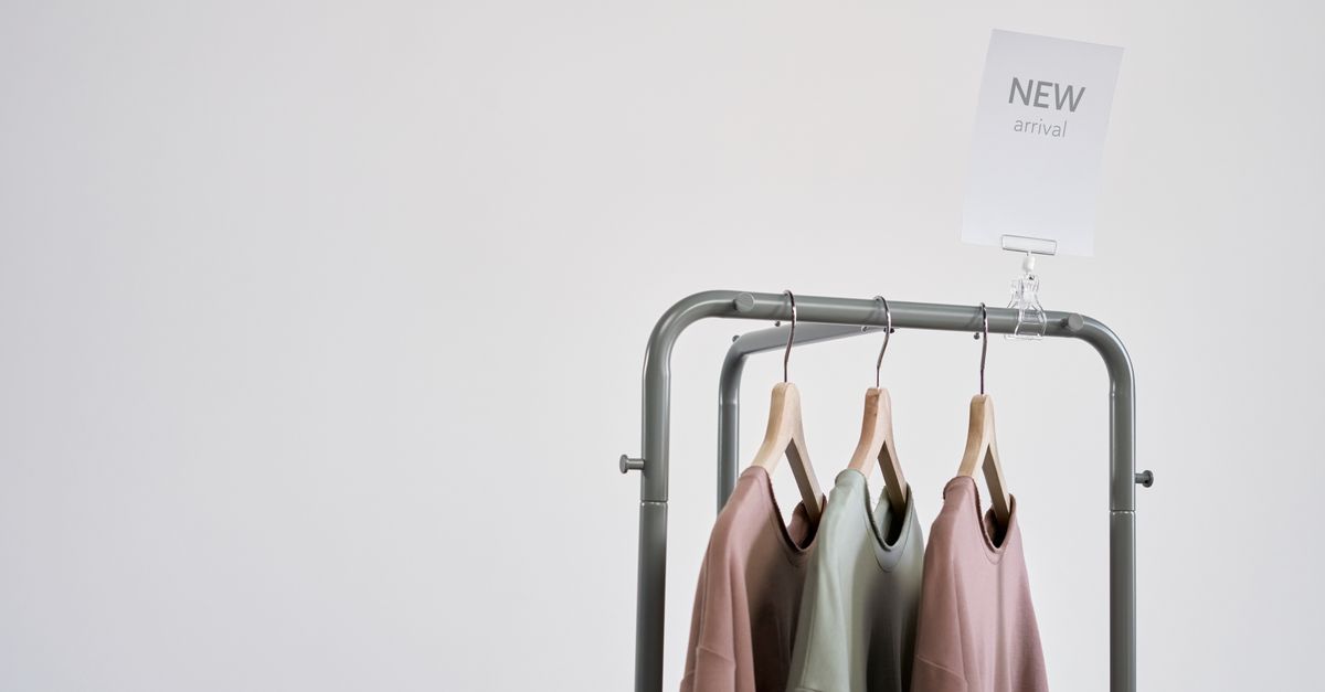 Stylish clothing on a rack with 'New Arrival' sign against a white wall.